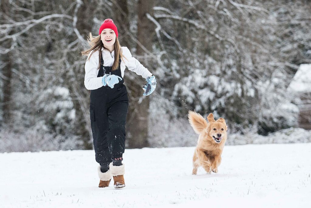 dog running through snow with owner